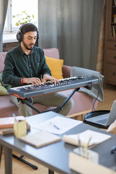 Genç müzik öğretmeni dizüstü bilgisayarın önünde piyano klavyesi çalıyor. — Stok fotoğraf