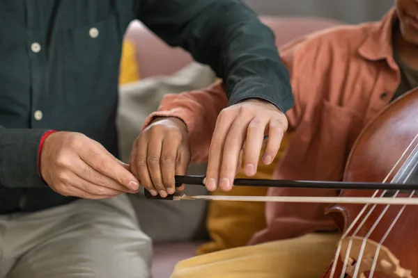 Hands of music teacher and his pupil playing cello — Stock Photo, Image