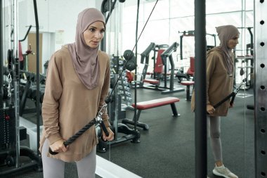 Genç güçlü sporcu kadın spor malzemelerinin kolunu çekiyor.