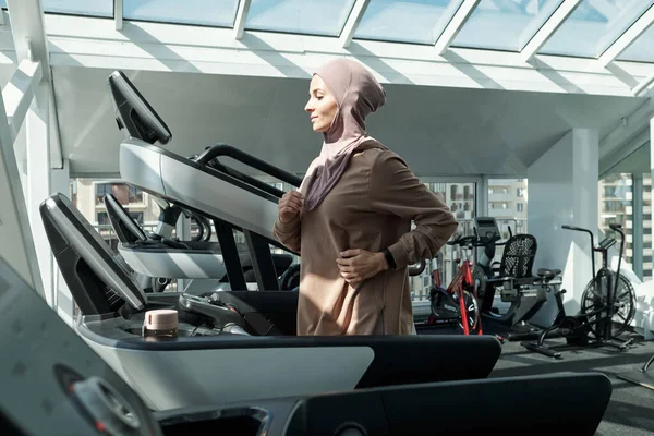 체육관에서 러닝 머신 위를 달리고 있는 젊은 이슬람 여성 — 스톡 사진