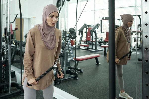 Genç güçlü sporcu kadın spor malzemelerinin kolunu çekiyor.