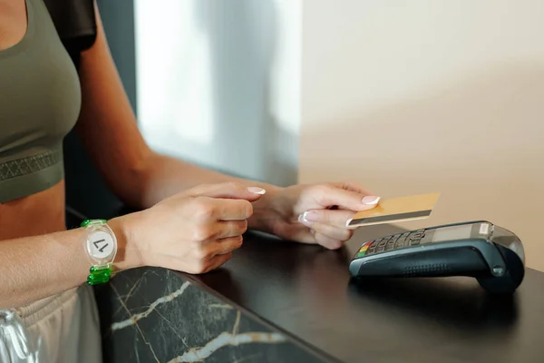 Mains de la jeune femme tenant la carte de crédit sur le terminal de paiement — Photo