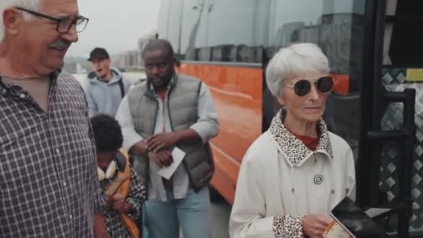 オープンバスのドアに立っている間 デジタルタブレット上の乗客の酸グリーンベストスキャニングチケットで女性バス指揮者の手持ち撮影 — ストック動画