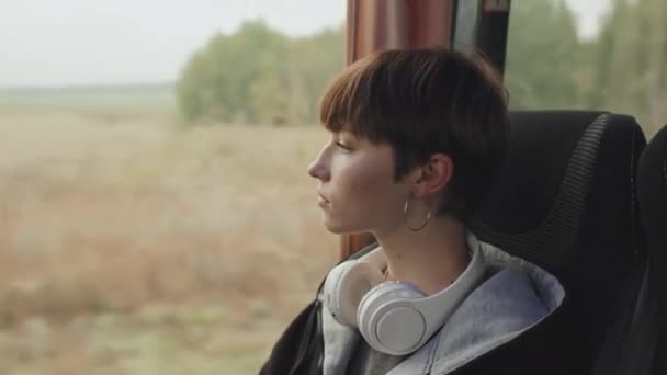 中特写短发少女坐在车窗边欣赏音乐时乘坐的风景 — 图库视频影像