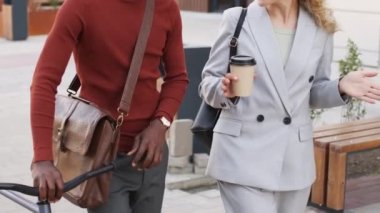 Sokakta yürürken iletişim kuran genç, çok ırklı iş kadınlarının yavaş çekimleri. Kadın iş ortağının fikirleri paylaşmasını dinlerken bisiklet taşıyan Afro-Amerikalı bir adam.