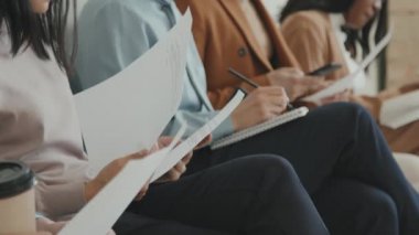 Röportaj için sırada oturan ve başvuru formlarını okuyan tanınmayan erkek ve kadın iş başvurularının orta bölüm çekimi
