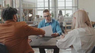 İşten çıkarıldıktan sonra İK yöneticisi ve yöneticiyle tartışan kızgın erkek çalışanın orta boy fotoğrafı. Kağıdı yırtıp atıyor, sonra da ofisten fırlayıp gidiyor.