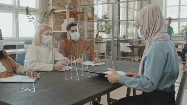 流感大流行期间 穿着头巾和面罩坐在防滴滴保护屏后的穆斯林女性求职者的跟踪照片和求职面试时的歌唱文件 — 图库视频影像
