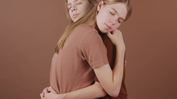 Genç Ikiz Kız Kardeşlerin Kahverengi Arka Plana Sarılmalarını Çek — Stok video