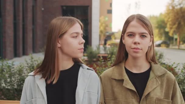 Håndholdt Sporingsbilde Unge Identiske Tvillingsøstre Som Sitter Benken Poserer Kamera – stockvideo