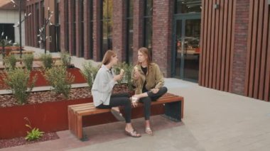 Dışarıda bankta oturup dondurma yerken sohbet eden mutlu ikiz kız kardeşlerin fotoğrafını çekiyorum.