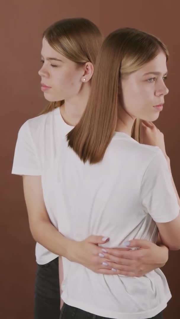 티셔츠를 배경에서 고립된 포즈를 취하는 아름다운 쌍둥이 자매의 — 비디오