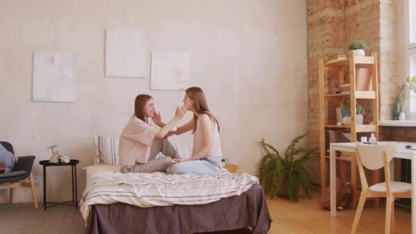 顔中出ししながらベッドに座って笑っている幸せな双子の姉妹のPanショット — ストック動画
