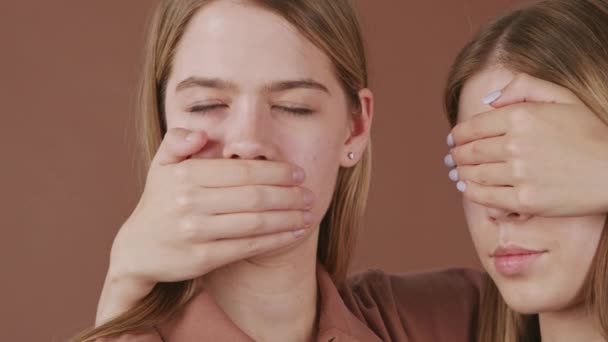 Panning Close Portrait Shot Young Twin Women Covering Mouth Eyes — Stock Video