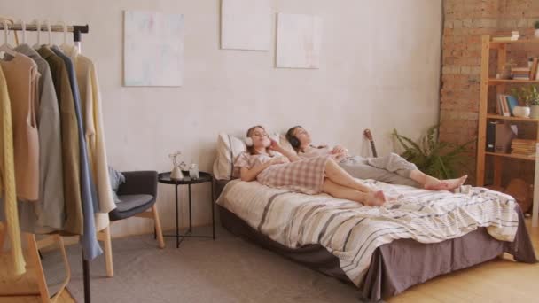 Pan Shot Young Twin Sisters Lying Bed Enjoying Music Headphones — Stock Video