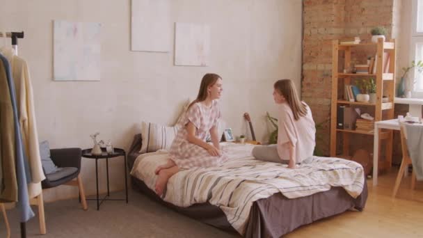 Pan Shot Cheerful Twin Sisters Sitting Bed Cozy Room Chatting — Stock Video