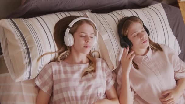 Handheld Top View Shot Young Twin Sisters Lying Bed Listening — Stock Video
