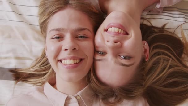 쌍둥이 소녀들 침대에 카메라를 보면서 위에서 가까이에서 보인다 — 비디오
