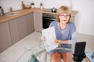 Canlı yayın sırasında kâğıda bakan kendinden emin olgun bir öğretmen.