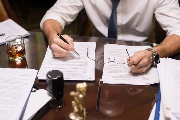 Reifer Geschäftsmann hält Stift über Dokument, während er es liest — Stockfoto
