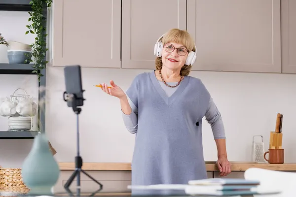 Gelukkig volwassen vrouw student in hoofdtelefoon praten in de voorkant van smartphone camera — Stockfoto