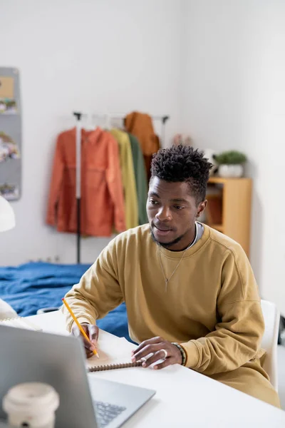 Africano chico en casualwear mirando la pantalla del ordenador portátil — Foto de Stock