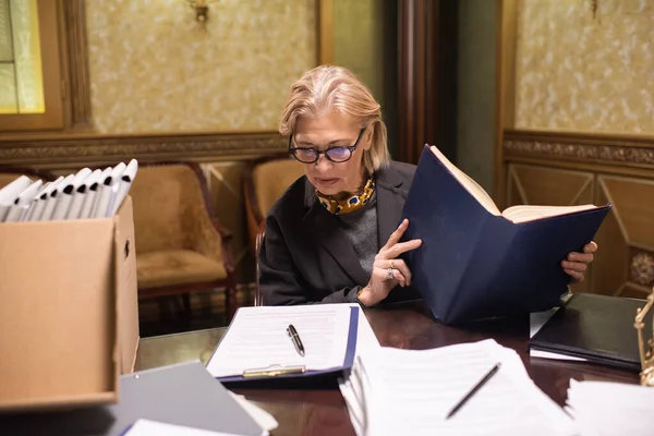 Λευκή γυναίκα δικηγόρος με ανοιχτό βιβλίο κοιτάζοντας το έγγραφο — Φωτογραφία Αρχείου