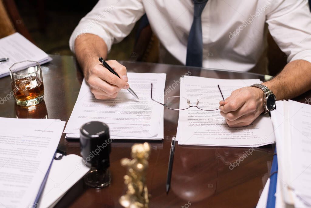 Mature businessman holding pen over document while reading it