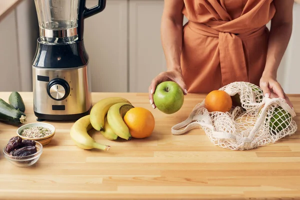 Las manos de la joven ama de casa sacando frutas frescas de la bolsa —  Fotos de Stock