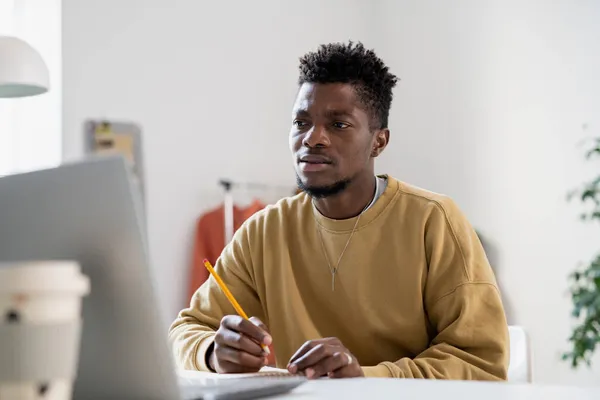 Tense young man with pencil looking at laptop screen — Stock Photo, Image