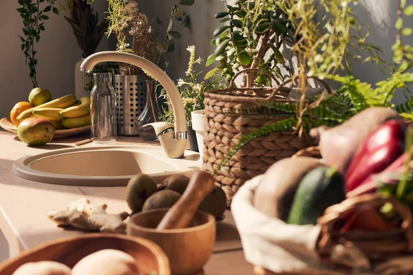 Parte della cucina illuminata dal sole con lavello circondata da frutta e verdura fresca — Foto Stock