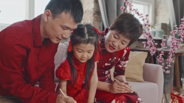 中国人の両親とかわいい5歳の女の子の手押しの傾きダウン中出し旧正月ポストカードを作成します — ストック動画