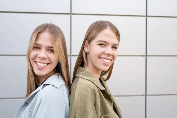 Faces of happy twins with long blond hair and toothy smiles — Stock Photo, Image