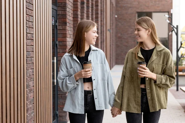 Cute adolescent girls with drinks taking walk in the city — Stock Photo, Image