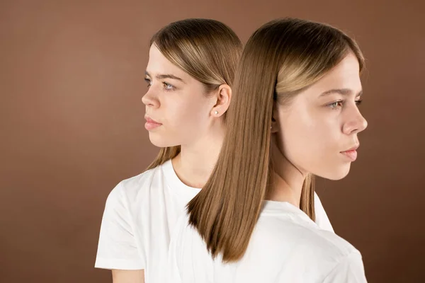 Serene ragazze gemelle con lunghi capelli biondi guardando nella direzione opposta — Foto Stock