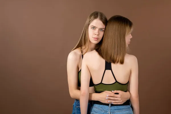 Adolescente com cabelo loiro e olhos azuis abraçando sua irmã gêmea — Fotografia de Stock
