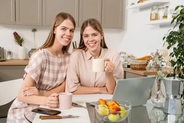 Roztomilé a veselá dvojčata s nápoji odpočinku v kuchyni — Stock fotografie