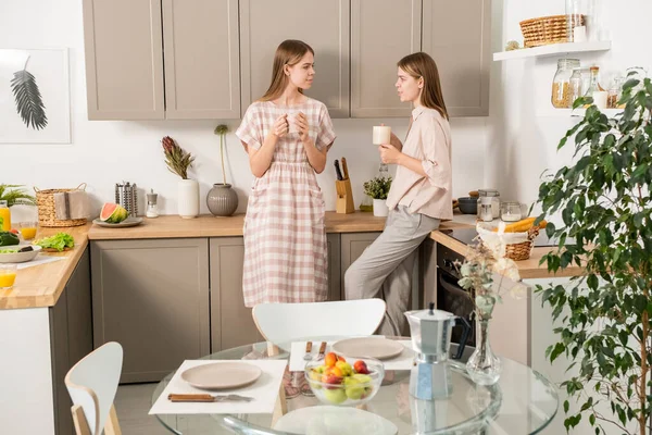 Δύο σύγχρονες έφηβες κοπέλες που πίνουν στην κουζίνα — Φωτογραφία Αρχείου