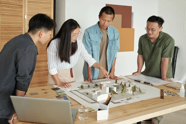Joven empresaria china señalando el diseño de la casa entre colegas — Foto de Stock