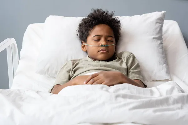Больной мальчик лежит в постели в больнице — стоковое фото