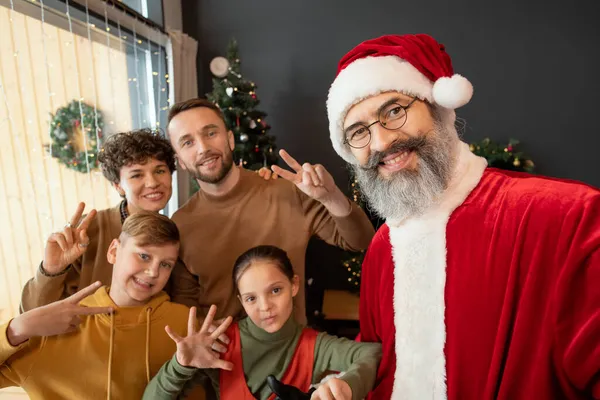Glimlachende kerstman poseren met familie op Kerstmis — Stockfoto