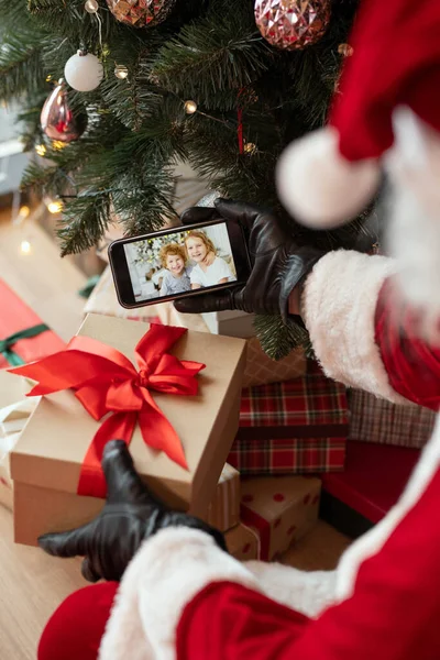Santa in guanti neri guardando foto — Foto Stock