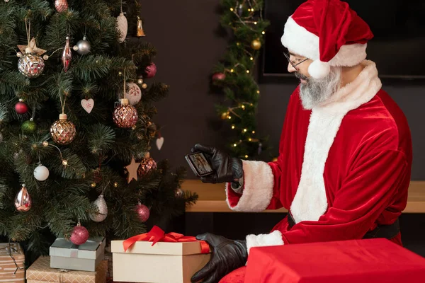 Santa Thief met behulp van Smartphone in de woonkamer — Stockfoto