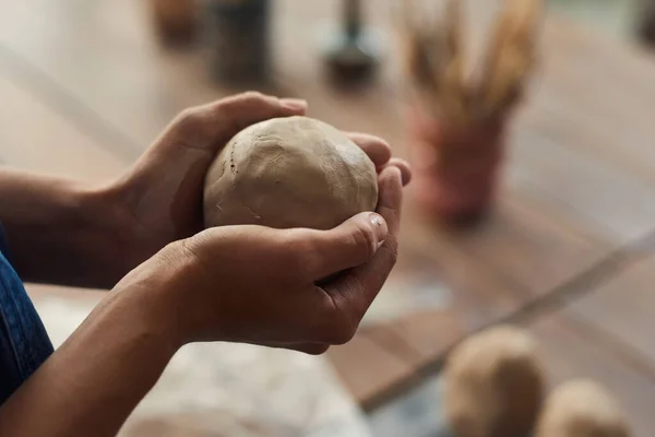 Руки молодої жінки, що тримає сферичну заготовку з глини — стокове фото