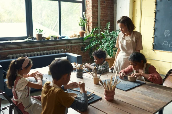 Group of cute intercultural schoolkids making earthenware — Stock Photo, Image