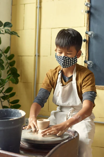 Азиатский школьник в защитной маске скульптор глиняный горшок — стоковое фото