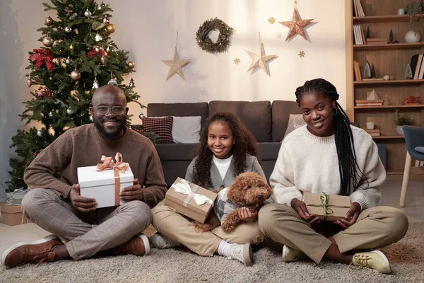 Jovem família africana feliz de três pessoas sentadas no chão em quarto decorado — Fotografia de Stock