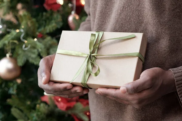 Mani di giovane uomo africano in possesso di regalo imballato in scatola — Foto Stock