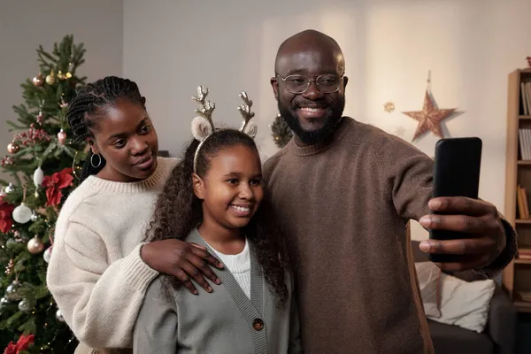 Gelukkig jong gezin van drie maken selfie door xmas boom — Stockfoto