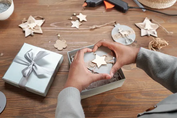 Handen van het meisje met handgemaakte kerst speelgoed over doos — Stockfoto